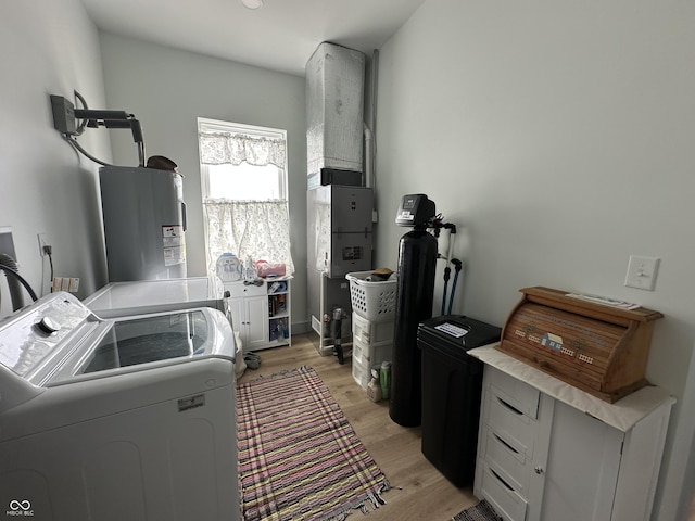 clothes washing area featuring light wood finished floors, water heater, laundry area, and washing machine and clothes dryer