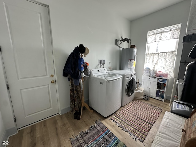 laundry area with baseboards, laundry area, light wood-style flooring, water heater, and washer and dryer