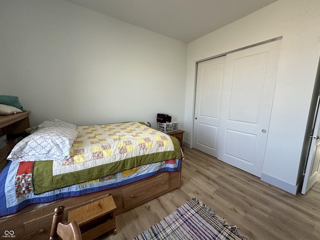 bedroom featuring wood finished floors, baseboards, and a closet