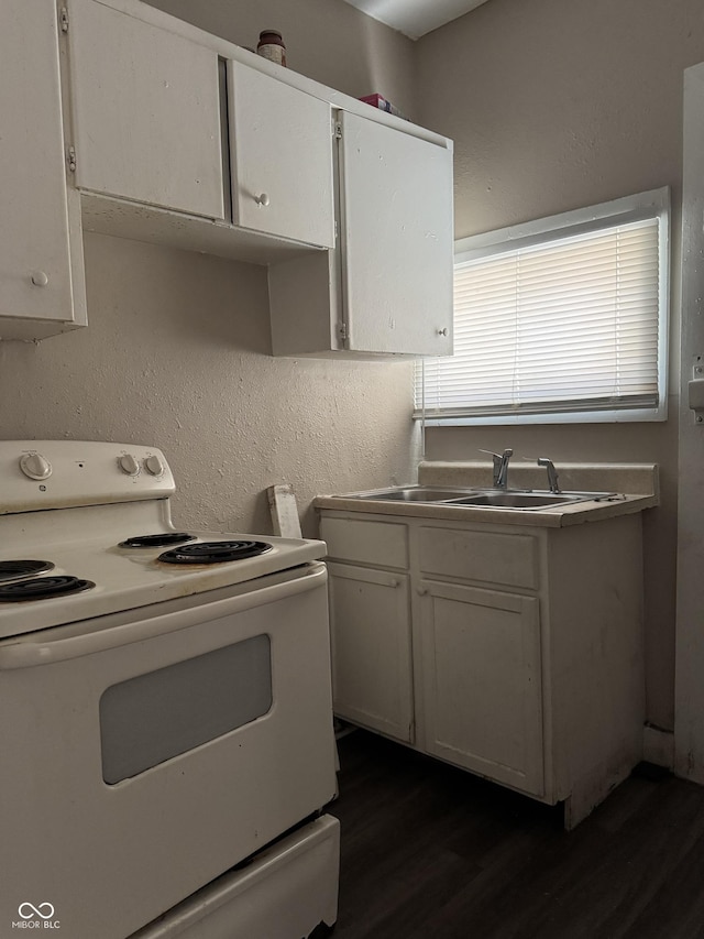 kitchen featuring white range with electric cooktop, dark wood-style flooring, a sink, white cabinets, and a textured wall