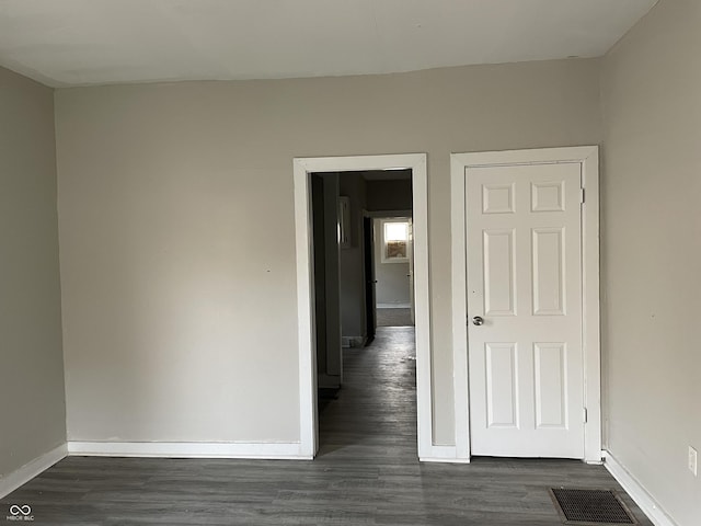 empty room with dark wood finished floors, baseboards, and visible vents