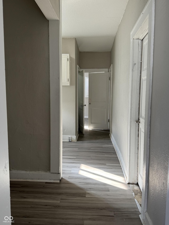 corridor with baseboards and wood finished floors