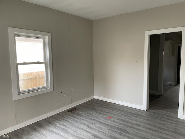 unfurnished room featuring visible vents, wood finished floors, and baseboards