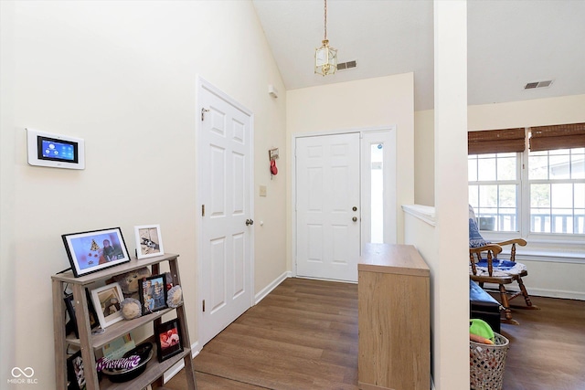 foyer entrance with visible vents, dark wood finished floors, and vaulted ceiling