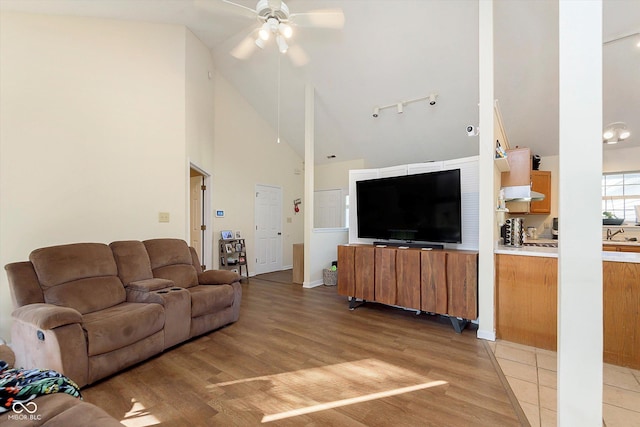 living room featuring high vaulted ceiling, rail lighting, light wood-type flooring, and ceiling fan