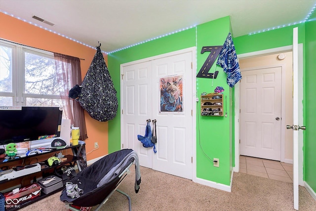 tiled bedroom with a closet, visible vents, baseboards, and carpet floors