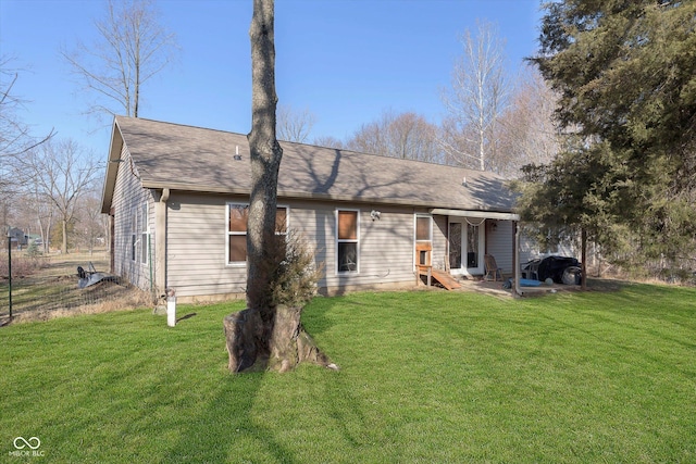 back of property featuring entry steps, a yard, and roof with shingles