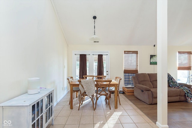 dining space featuring light tile patterned floors, visible vents, and vaulted ceiling