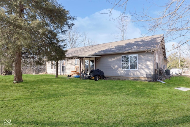 rear view of property with central air condition unit, a shingled roof, and a yard