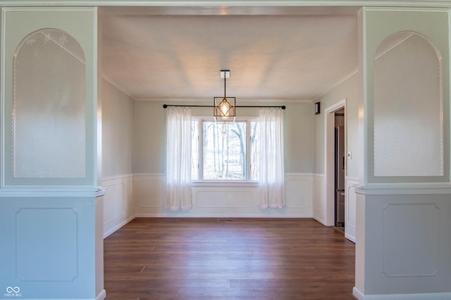 unfurnished dining area with wainscoting, ornamental molding, and wood finished floors