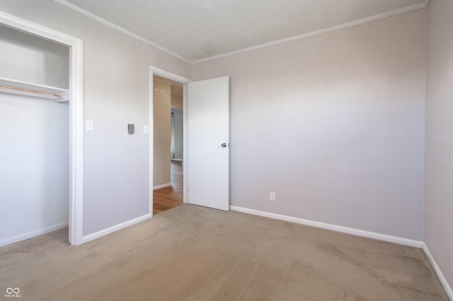 unfurnished bedroom featuring crown molding, carpet, baseboards, and a closet