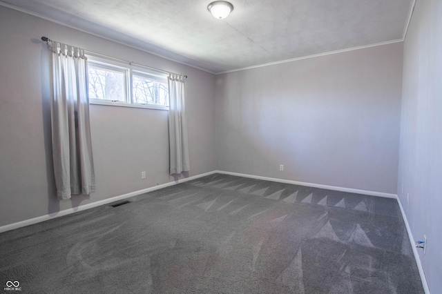 spare room with dark colored carpet, visible vents, baseboards, and crown molding