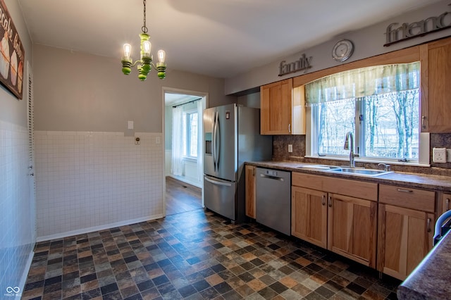 kitchen with a sink, dark countertops, appliances with stainless steel finishes, and pendant lighting