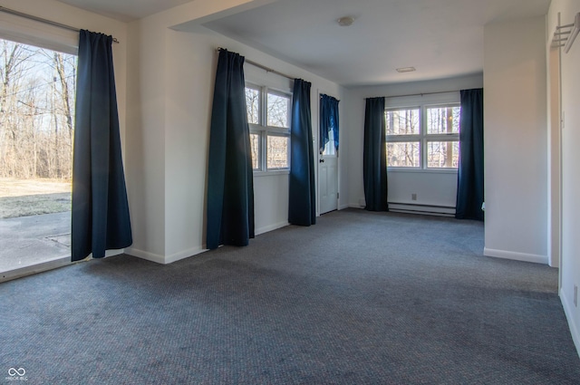 carpeted empty room with a wealth of natural light, a baseboard heating unit, and baseboards