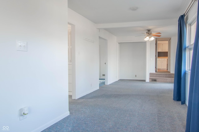 carpeted spare room featuring visible vents, baseboards, and ceiling fan