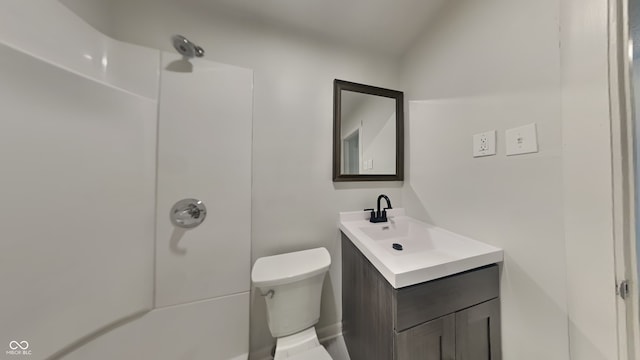 bathroom featuring toilet, vanity, and a shower