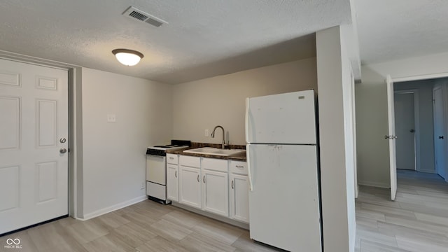 kitchen with white appliances, visible vents, a sink, white cabinetry, and dark countertops