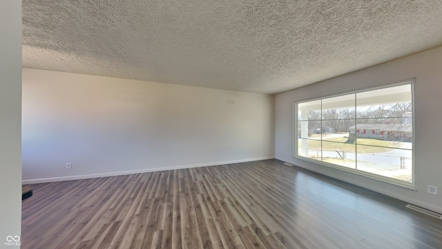 empty room featuring visible vents, baseboards, a textured ceiling, and wood finished floors