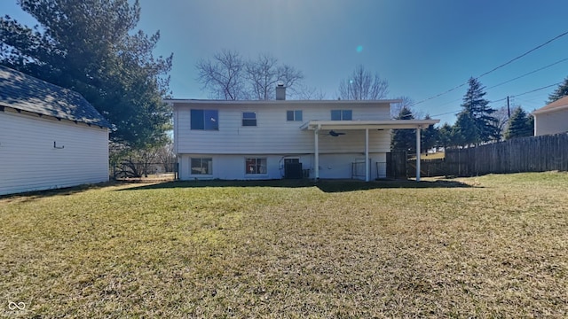 back of property featuring a lawn, central AC unit, and fence