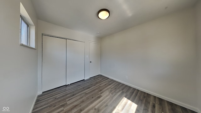 unfurnished bedroom with wood finished floors, baseboards, and a closet