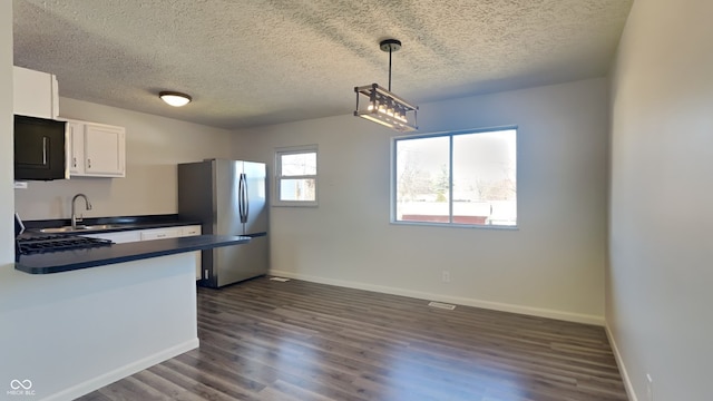 kitchen with dark countertops, dark wood finished floors, white cabinets, and freestanding refrigerator