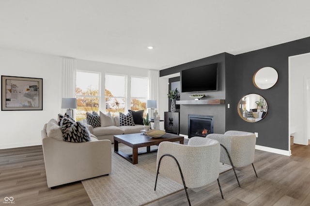 living area featuring recessed lighting, baseboards, wood finished floors, and a glass covered fireplace