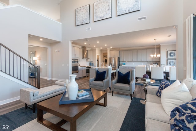 living room with a notable chandelier, visible vents, light wood-type flooring, and baseboards