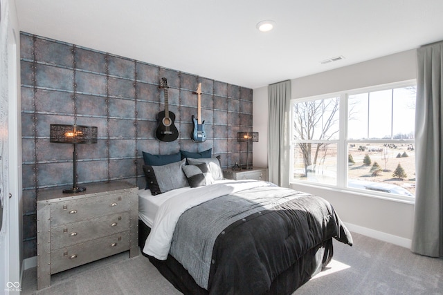 carpeted bedroom with visible vents, baseboards, and an accent wall