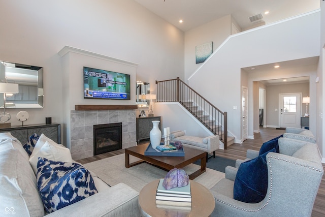 living area with wood finished floors, a high ceiling, baseboards, stairs, and a tile fireplace