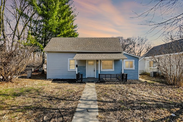 bungalow with central air condition unit, covered porch, and a shingled roof