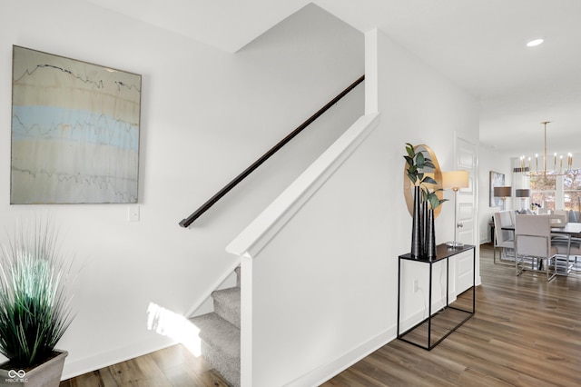 stairs featuring recessed lighting, baseboards, an inviting chandelier, and wood finished floors