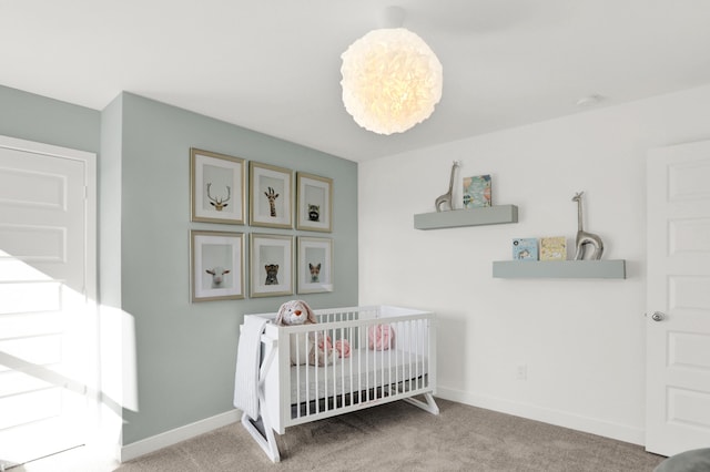 carpeted bedroom featuring baseboards and a nursery area