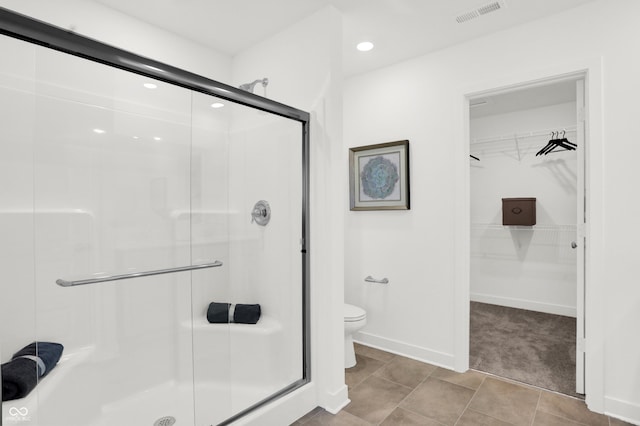 bathroom with baseboards, visible vents, a stall shower, a spacious closet, and toilet