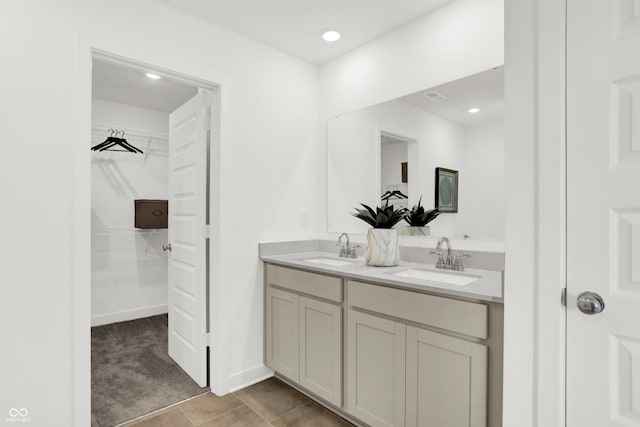 full bath with a walk in closet, double vanity, and a sink