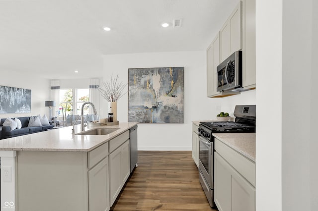 kitchen featuring a center island with sink, recessed lighting, appliances with stainless steel finishes, dark wood-style floors, and a sink