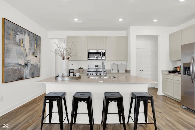 kitchen featuring a sink, stainless steel appliances, light wood-style floors, and a breakfast bar area