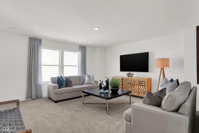 living area featuring baseboards and light carpet