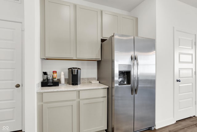 kitchen featuring light stone counters, wood finished floors, and stainless steel refrigerator with ice dispenser