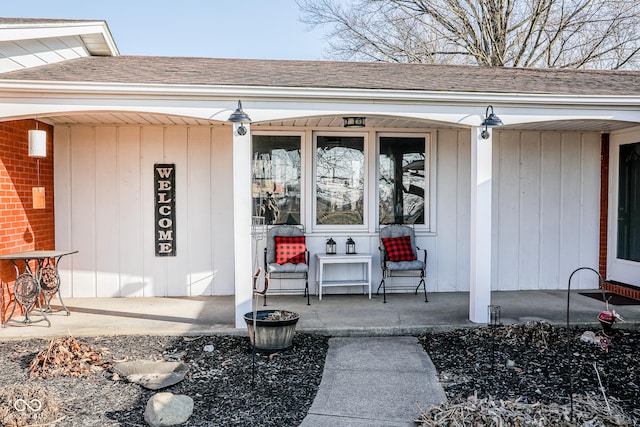 doorway to property with board and batten siding, covered porch, and a shingled roof