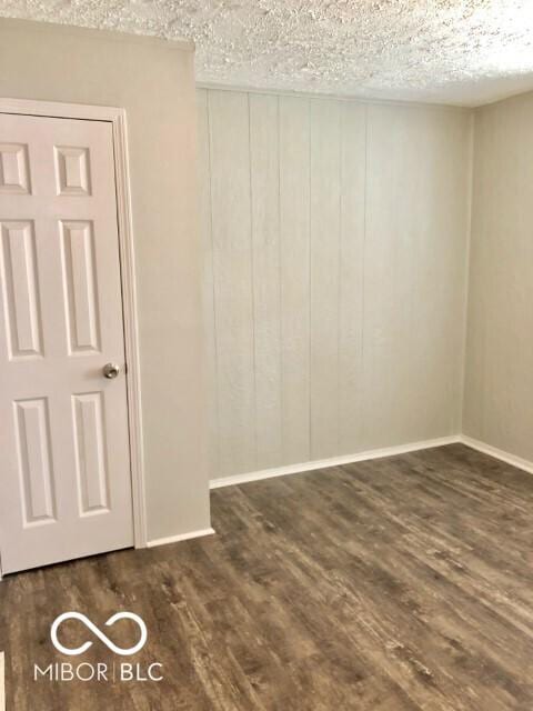 unfurnished room with wood finished floors, baseboards, and a textured ceiling