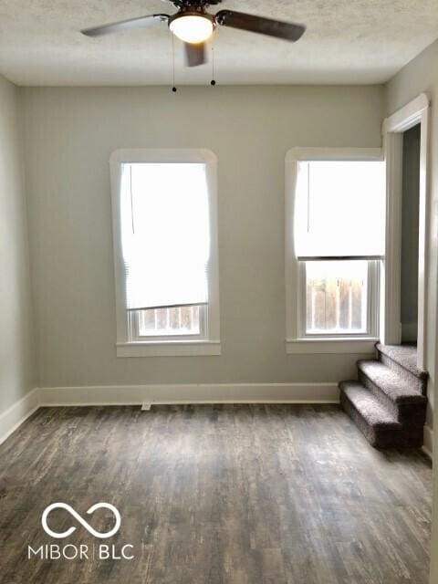 empty room featuring a textured ceiling, baseboards, and wood finished floors