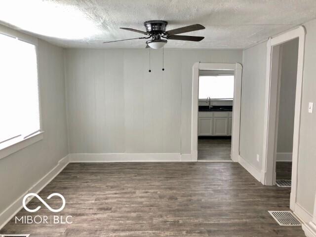 empty room featuring visible vents, a textured ceiling, wood finished floors, and a sink