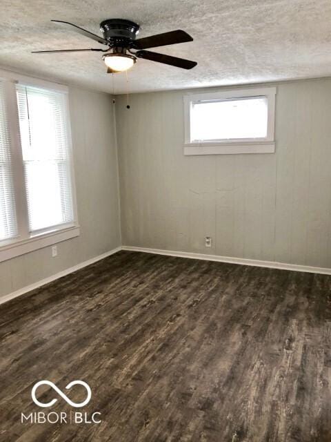 empty room with dark wood-style floors, baseboards, and a textured ceiling