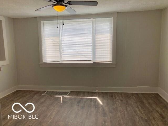 empty room featuring visible vents, a textured ceiling, wood finished floors, baseboards, and ceiling fan