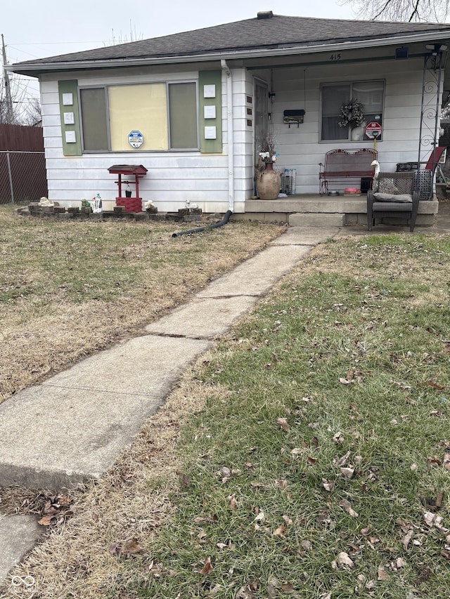 view of front of property featuring a porch, a shingled roof, a front yard, and fence