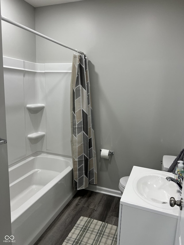 bathroom with vanity, wood finished floors, baseboards, shower / bath combination with curtain, and toilet