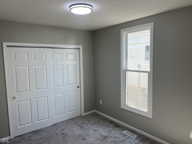 unfurnished bedroom with multiple windows, baseboards, visible vents, and carpet floors