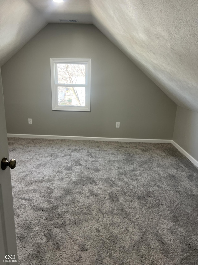 bonus room with visible vents, a textured ceiling, carpet floors, baseboards, and vaulted ceiling