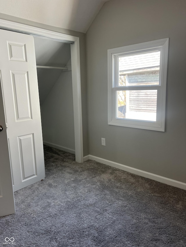 unfurnished bedroom with baseboards, lofted ceiling, carpet, and a closet