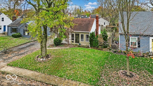 view of front of home featuring a shingled roof, a front yard, aphalt driveway, and a chimney